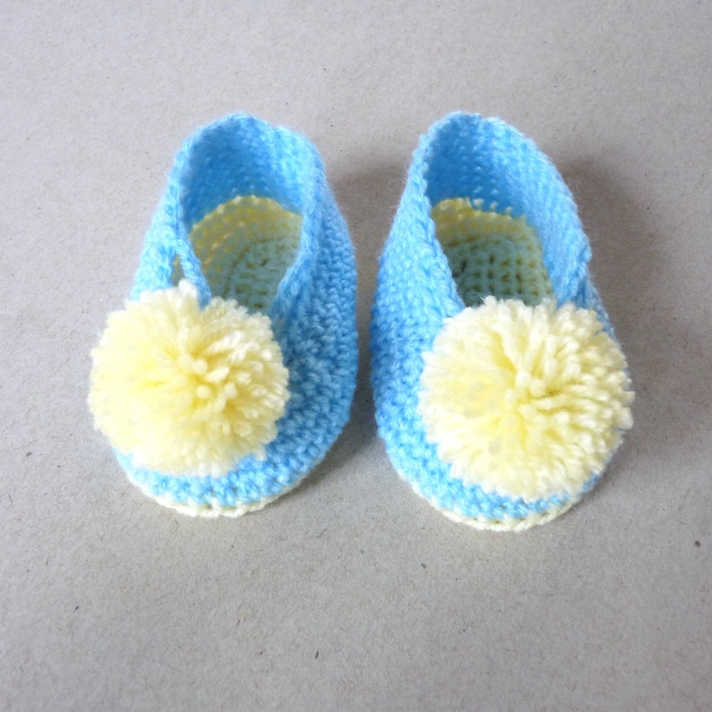 crochet baby shoes with pompoms, blue and yellow