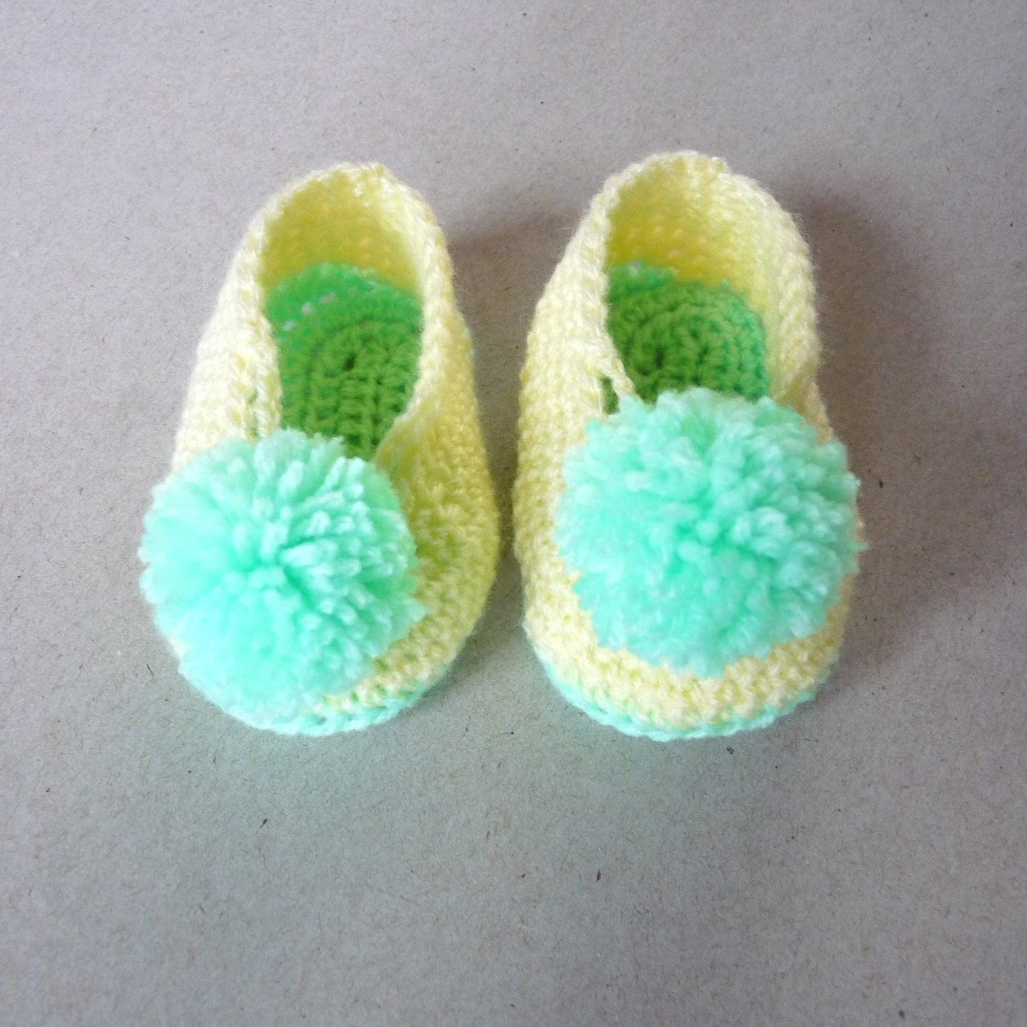 crochet baby shoes with pompoms, green and yellow