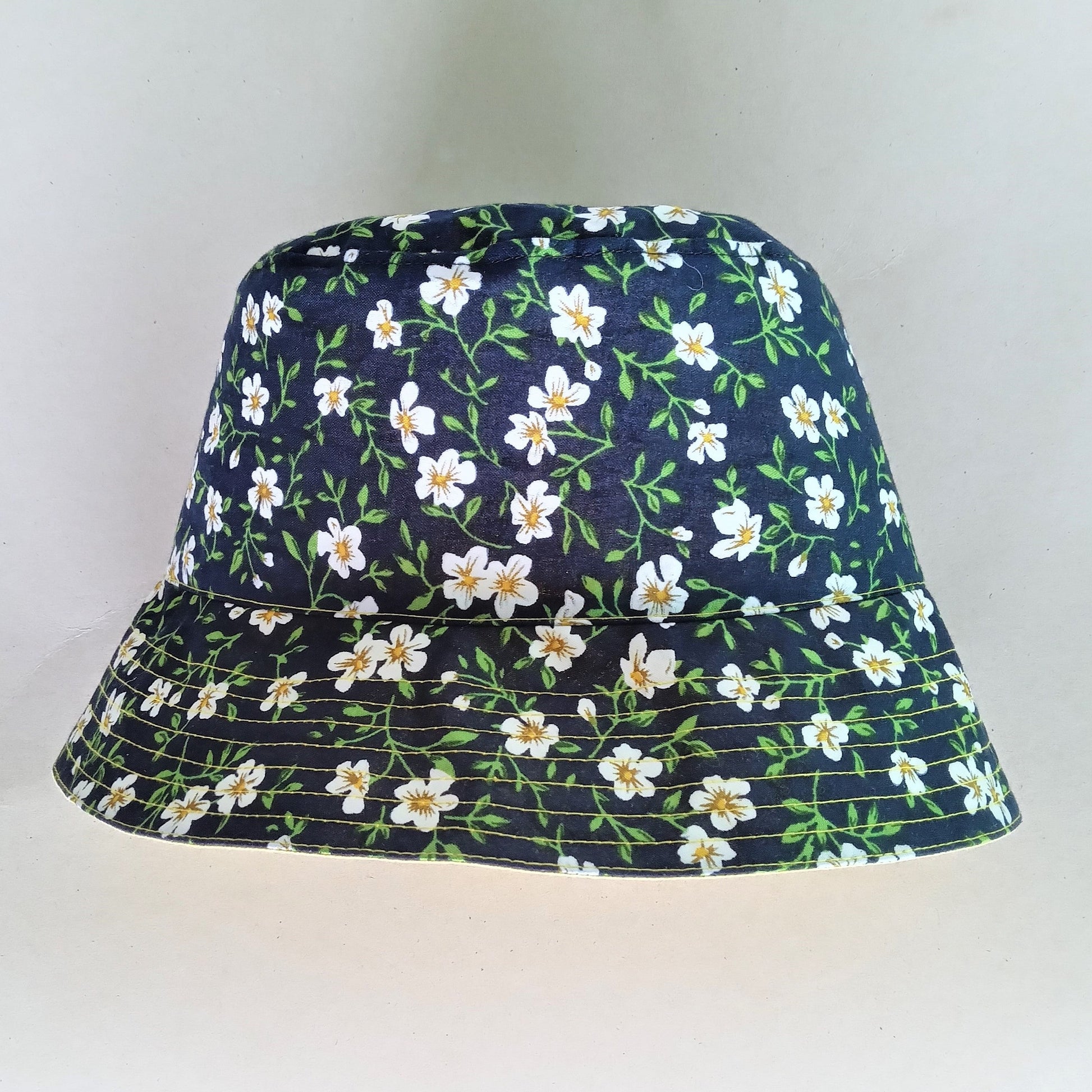 black white floral cotton fabric bucket hat. Available in 3 sizes. One side is black and white floral and the other side is yellow.